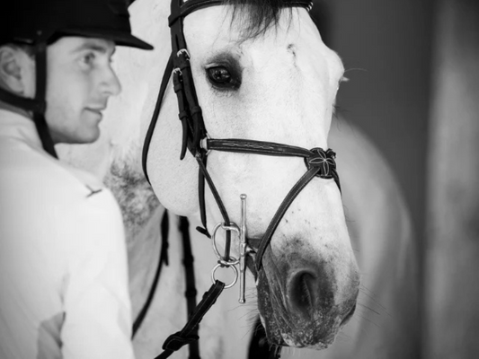 Black and white image of a man next to a white horse wearing a bridle and ARJ bit courtesy of AJRSport.com