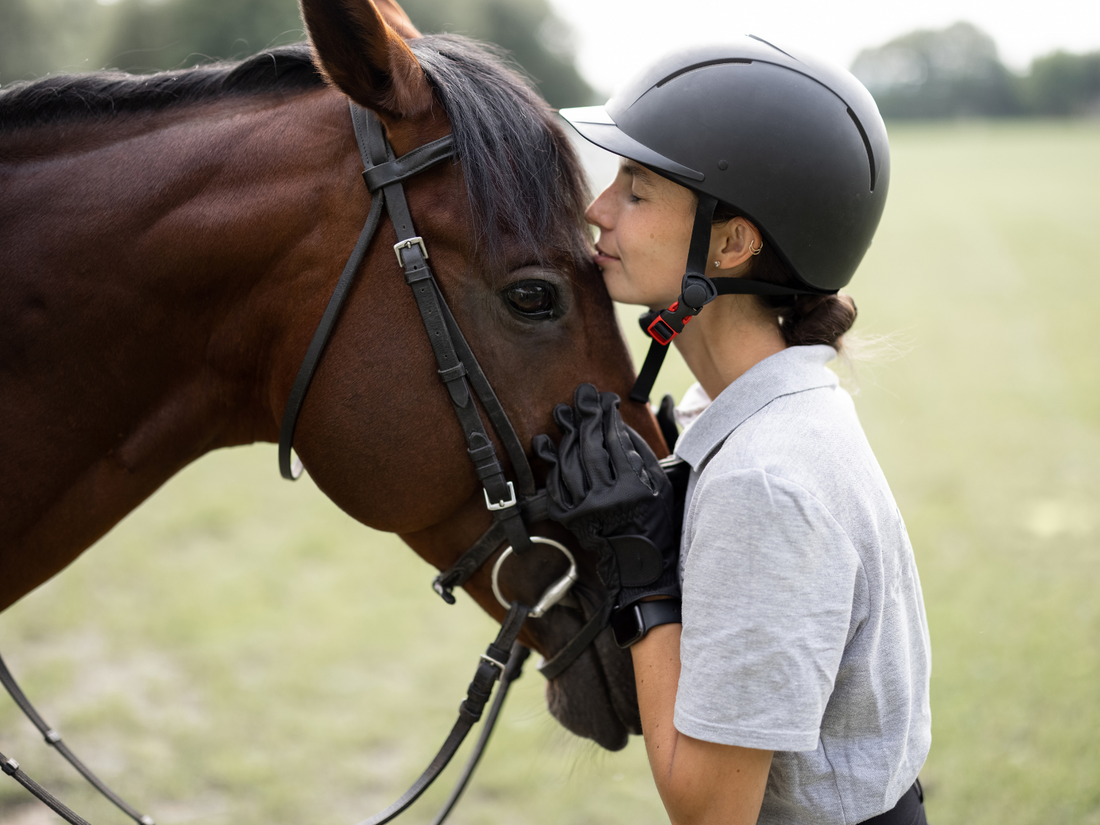 Woman kissing her horse on the forehead